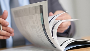SPECTRUM Kundenmagazin Person blättert in einem Magazin als Bild für Branchennews, Fachbeiträge und SPECTRUM Publikationen