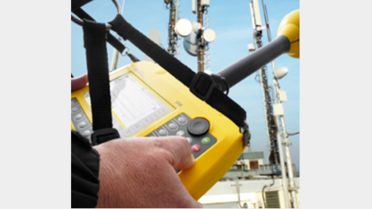 Mesure du rayonnement électromagnétique avec appareil portable Gros plan sur une personne utilisant un appareil portable jaune de mesure des champs électromagnétiques devant des antennes de diffusion – illustre les services d’évaluation des risques et de sensibilisation de LS telcom.