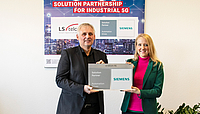  Two individuals holding a sign announcing LS telcom AG as a Siemens Solution Partner for Automation Drives.