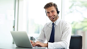 Trainer mit Headset und Laptop als Bild für Online-Seminare und digitale Schulungen.