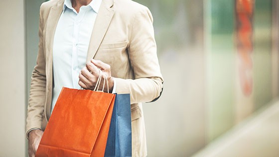 A man holding colorful shopping bags in a modern retail environment.